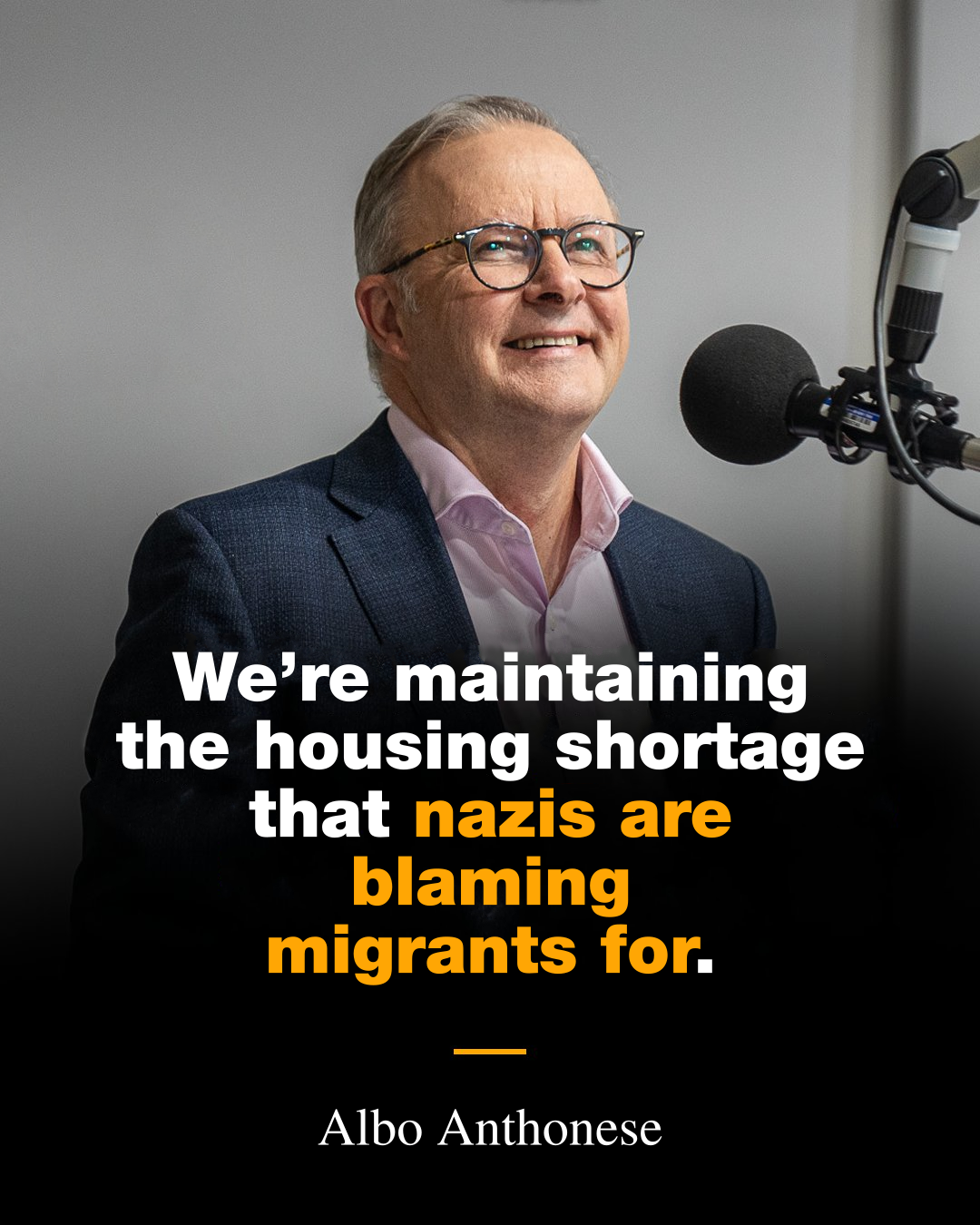A picture of Anthony Albanese at a recording studio microphone, smiling and looking upwards, a propaganda photo dream betrayed by the fact this fuck doesn't believe in anything. The text reads "We';re maintaining the housing shortage that nazis are blaming migrants for." and then deliberately misspells his name as Albo Anthonese.